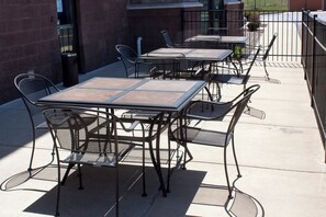 Mobilier d’extérieur pour patio, comprenant des chaises et des tables en métal, disposé sur une surface en béton.