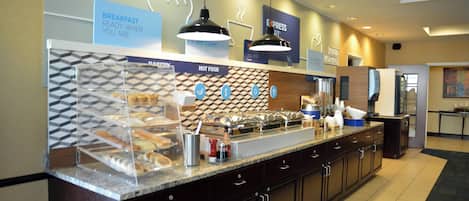 Zona de desayuno tipo buffet con señalización clara para comida caliente y una variedad de pasteles.