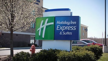 Señal de Holiday Inn Express & Suites con una vista clara de la entrada del edificio y un hidrante rojo al frente.