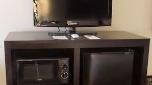 Een donkerhouten kastje met een flatscreen televisie, een magnetron en een minibar.