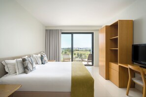 A hotel room with a bed, a TV, a desk, and a balcony with a view.