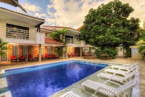 A swimming pool with lounge chairs and a tree in the background.