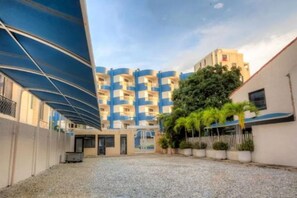 A building with a blue and white facade, a gravel courtyard, and a covered walkway.