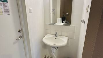 Un baño pequeño y limpio con lavamanos, espejo e instalación de cerámica.