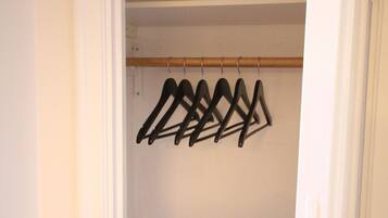 Een kast met een houten stang en zwarte ophangers.
