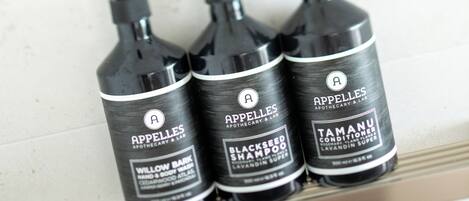 Three black bottles of shampoo on a white shelf.
