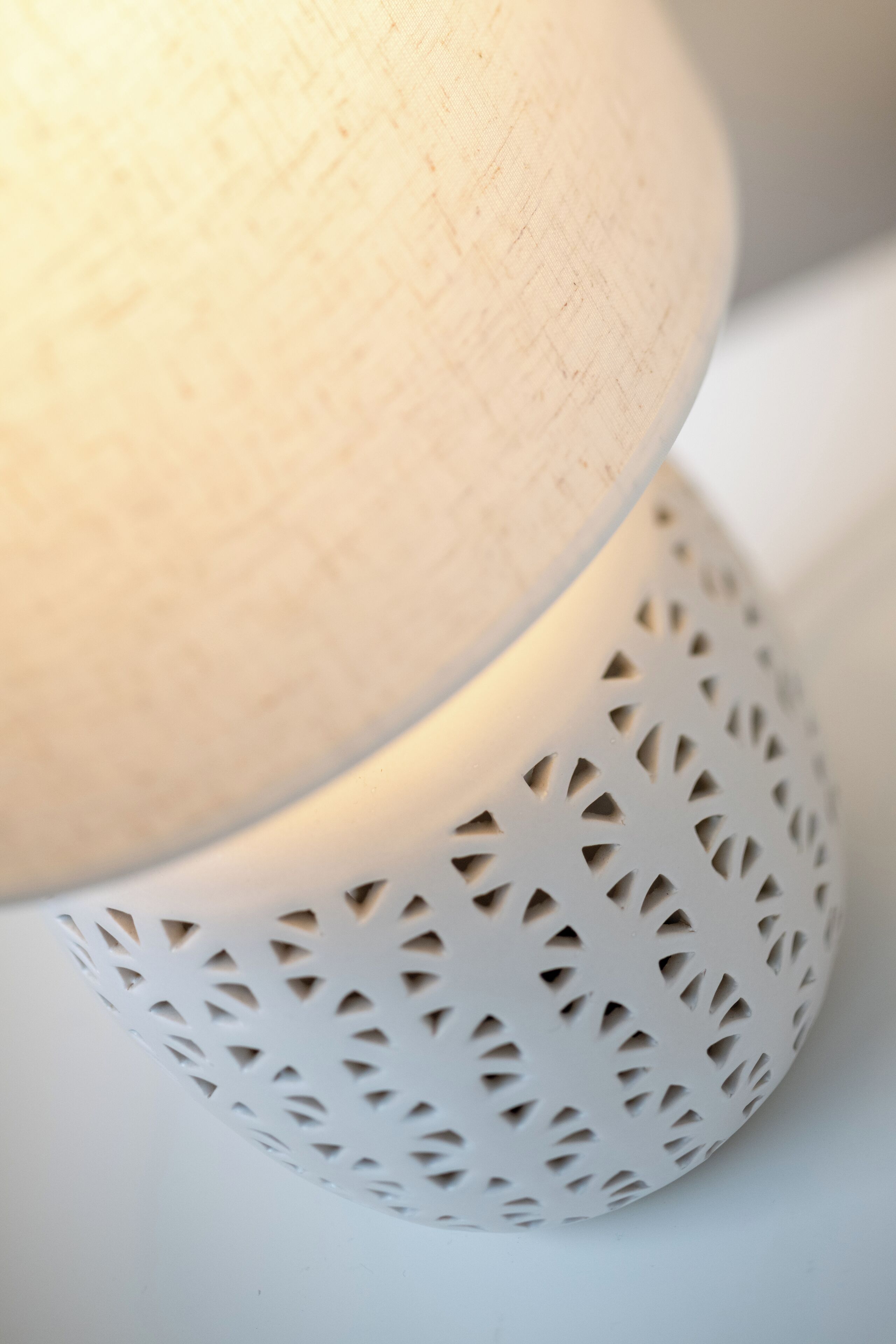 A close-up of a wooden lamp with a perforated metal base.