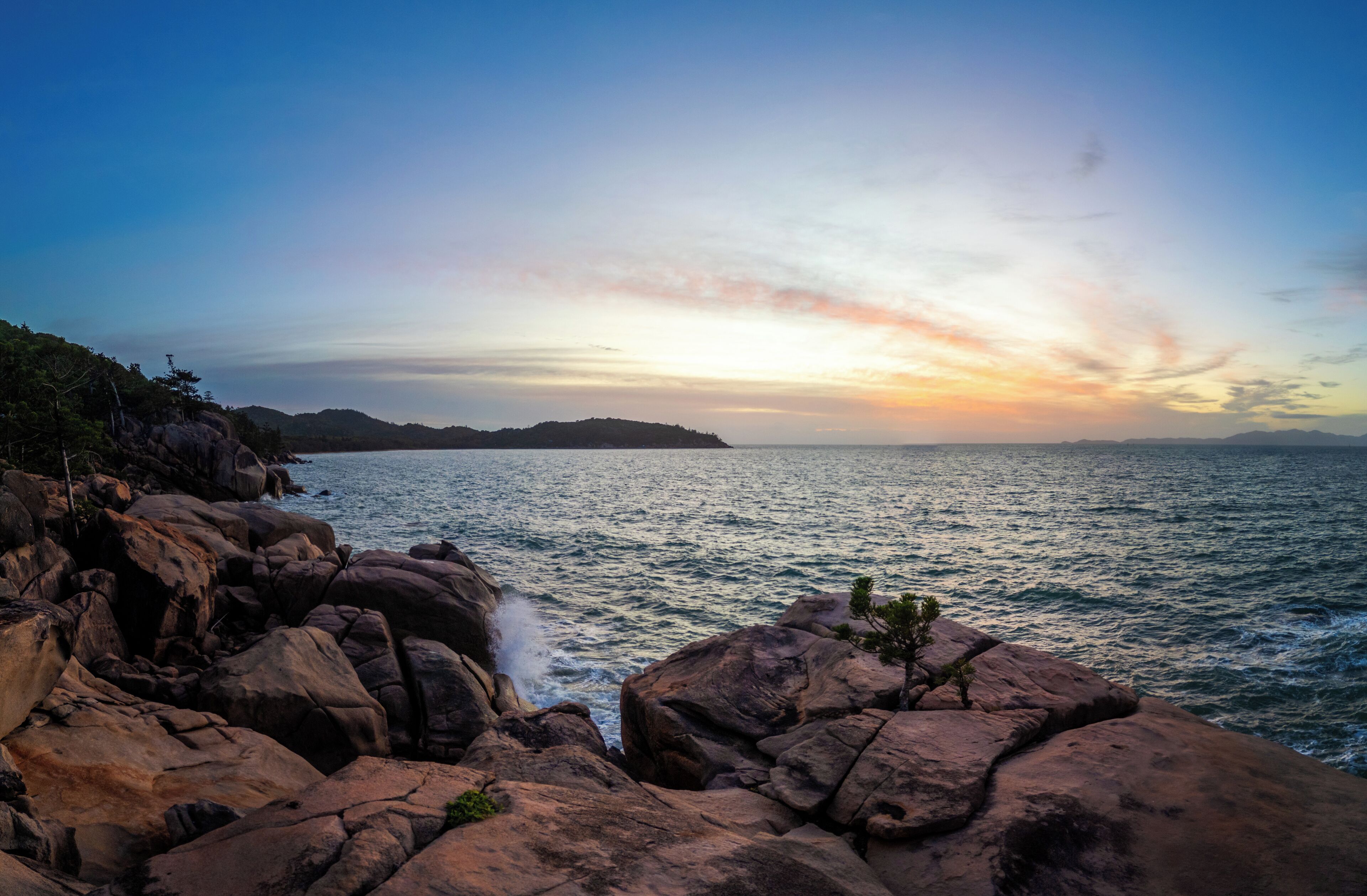 Paesaggio costiero con grandi rocce e vista sul mare.