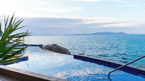 Ein Pool ohne Ende mit freiem Blick auf das Meer und ferne Berge.