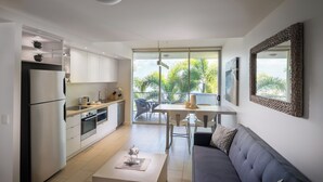 Eine moderne Küche mit Essbereich, einer Sitzecke und einem großen Fenster mit Blick auf Palmen.