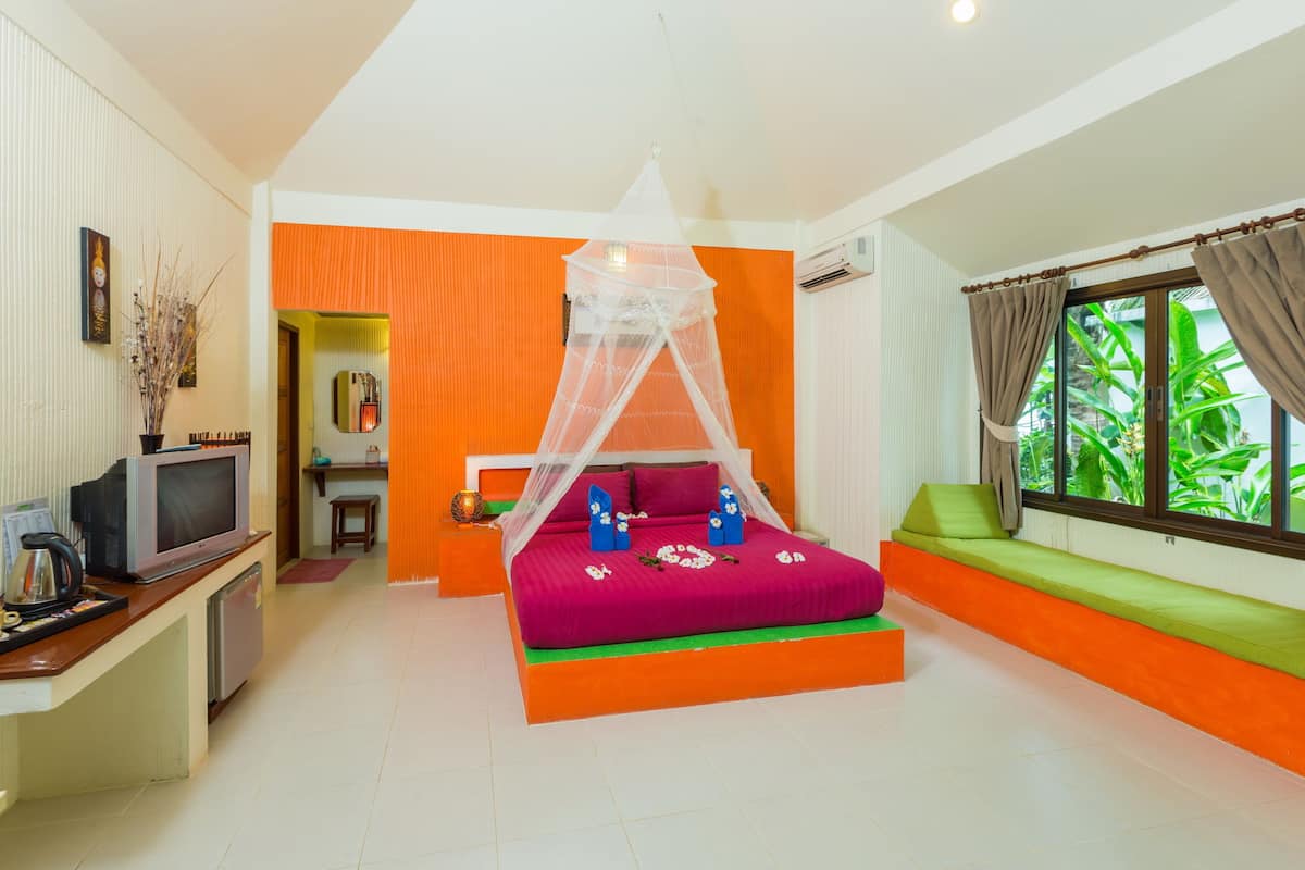 Quarto com cama, televisão e janela com cortinas.