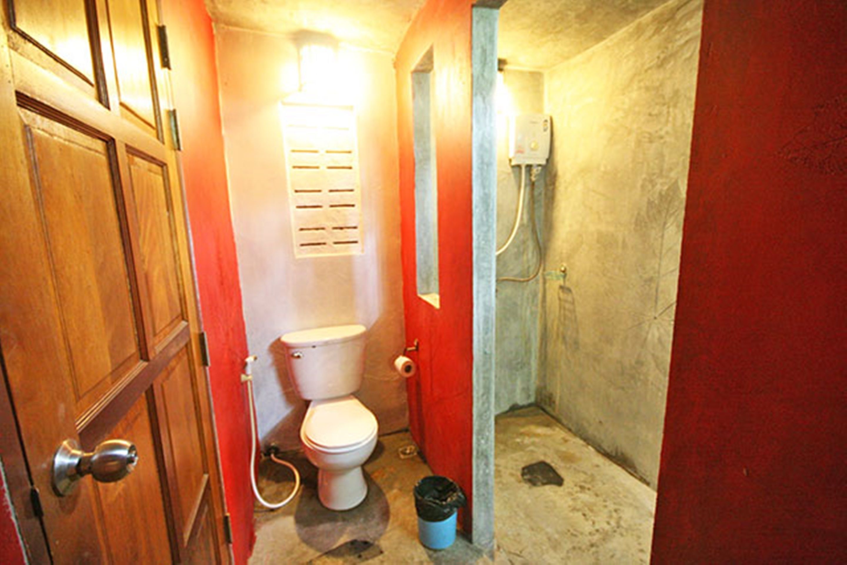 Un baño pequeño y funcional con inodoro, ducha y puerta de madera.