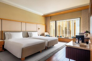 A hotel room with two beds, a desk, and a large window. - Hotel Okura Macau (Cotai)