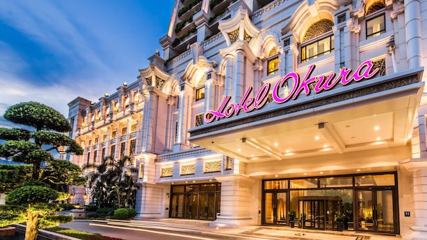 Imponente entrada de hotel con un letrero iluminado, amplias puertas de cristal y detalles arquitectónicos de estilo clásico.
