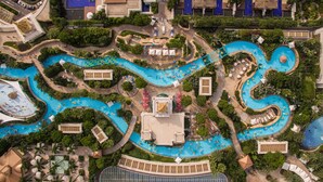 Vista aérea de un complejo turístico con varias piscinas interconectadas, senderos peatonales y abundante vegetación.