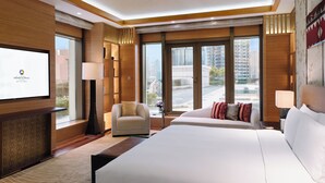 Habitación de hotel con una cama grande, un sofá, un televisor y vistas a la ciudad.