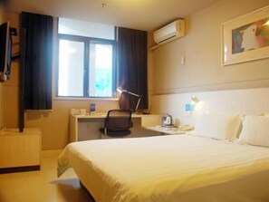 A hotel room with a bed, a desk, a chair, an air conditioner, and a window with curtains. - Jinjiang Inn Kunshan Train Station (Suzhou)