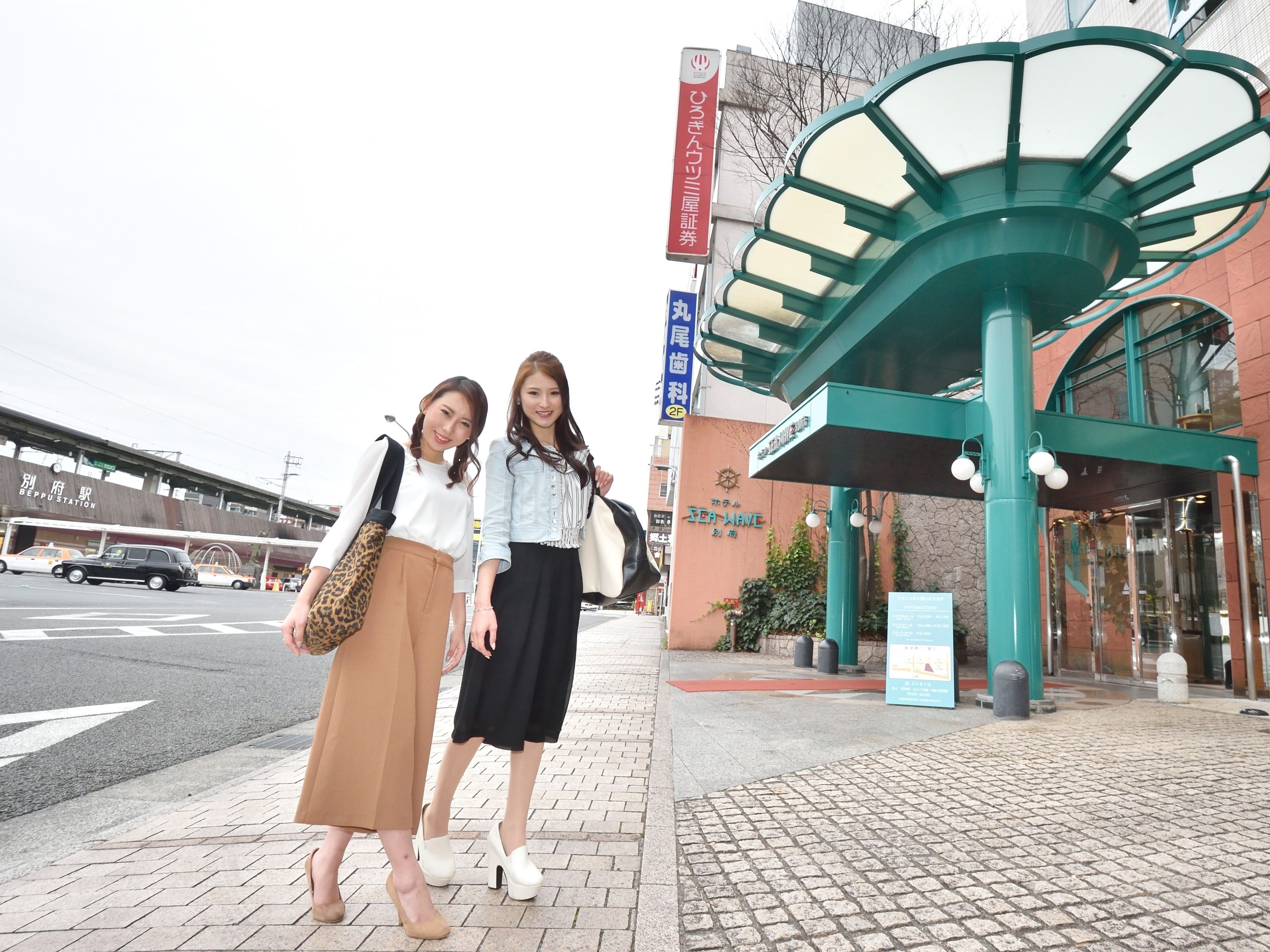 Two women standing in front of a building with a sign that reads "Sea Wave".