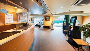 Een modern interieur met een receptiebalie, een ontbijtbuffet en zelfbedieningskiosken.