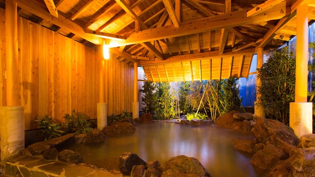 Een houten spa met een stenen warmwaterbron, omringd door rotsen en planten.