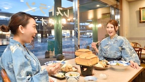 Een eetgedeelte met een tafel gedekt voor twee personen, met traditionele Japanse gerechten en een theepot.
