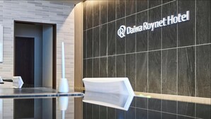 A modern reception area with a dark tiled wall and a glass counter.