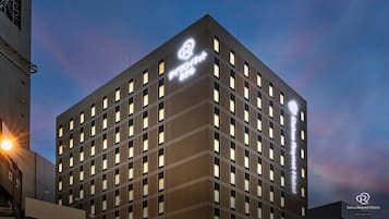 Un hotel Daiwa Roynet de diseño moderno, con una estructura de ventanas en forma de cuadrícula y un logotipo destacado en la fachada.
