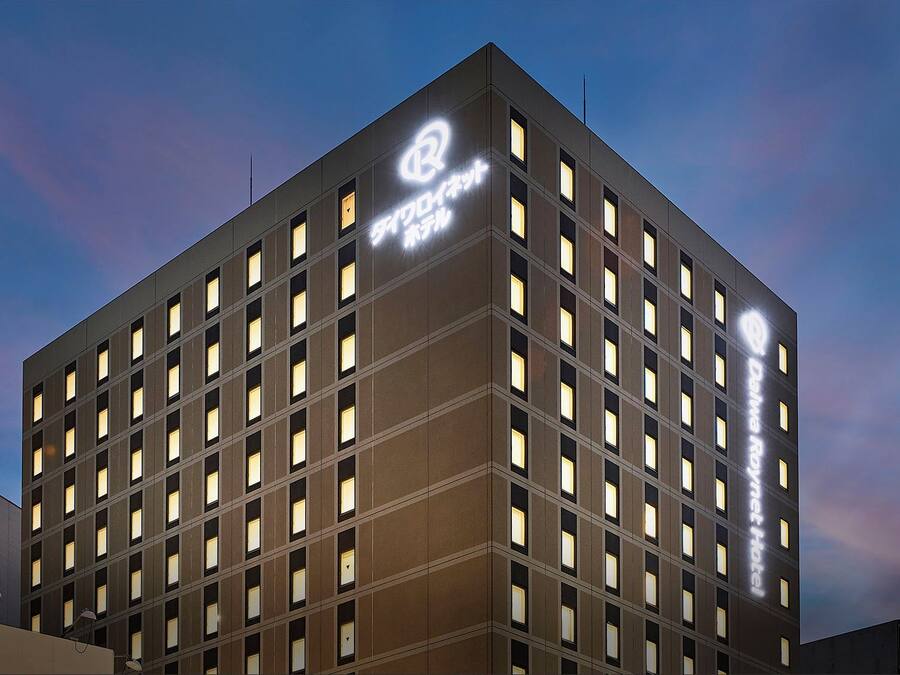 Un hotel Daiwa Roynet de diseño moderno, con una estructura de ventanas en forma de cuadrícula y un logotipo destacado en la fachada.
