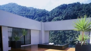 Um espaço ao ar livre moderno com deck de madeira, janelas amplas e plantas em vasos.