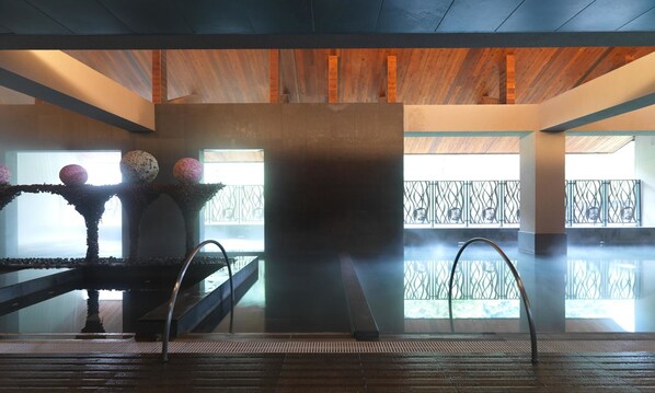 A modern interior with a wooden ceiling, a central column, and a view of a balcony with a metal railing.