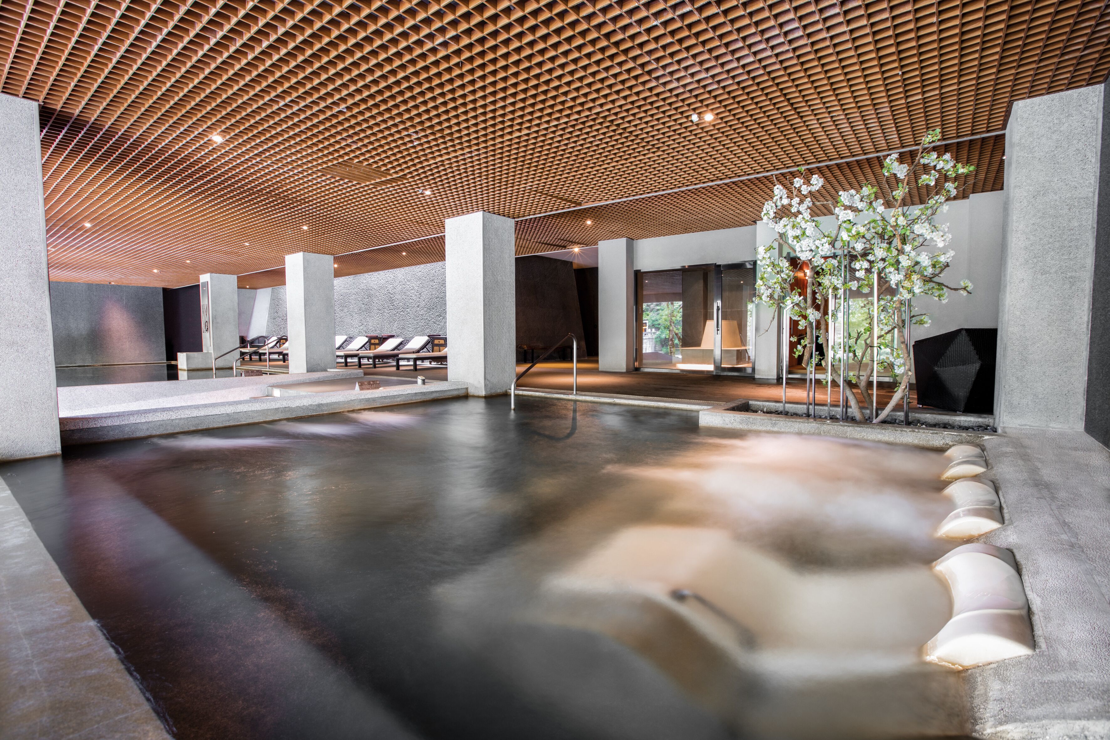 A modern spa area with a heated floor, seating area, and a wooden ceiling.