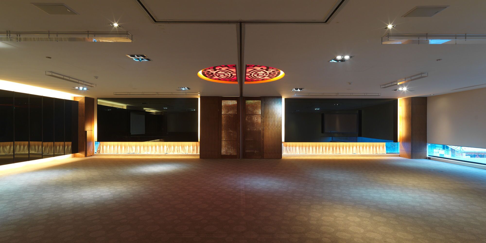 Un interior espacioso y moderno con un panel de madera central, iluminación empotrada y un suelo estampado.