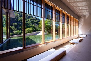 Un espace spa moderne doté de grandes fenêtres, d’une piscine et de sièges disposés le long des fenêtres.