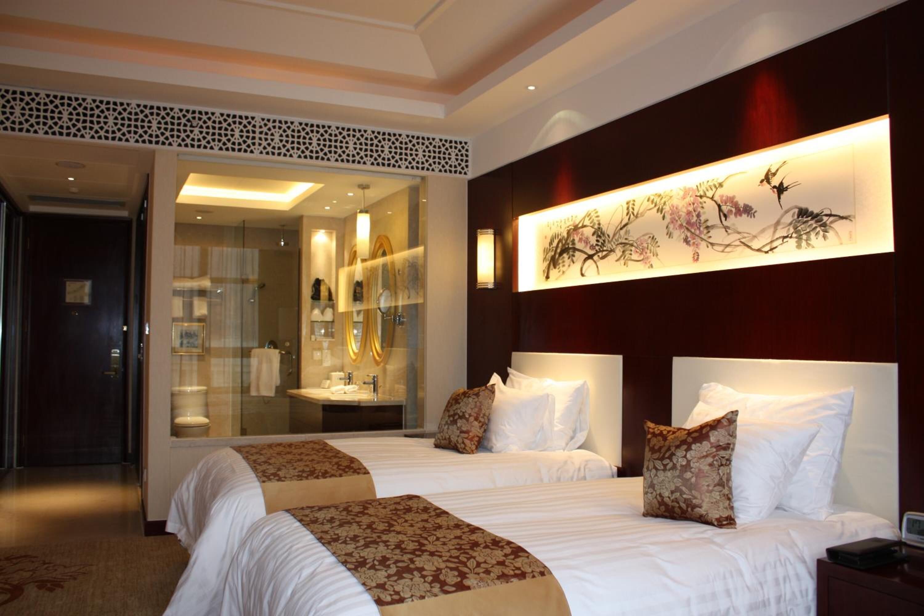 A hotel room with two beds, a large mirror, and a wall-mounted artwork.