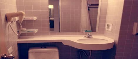 A small bathroom with a toilet, sink, and a hairdryer on the wall.