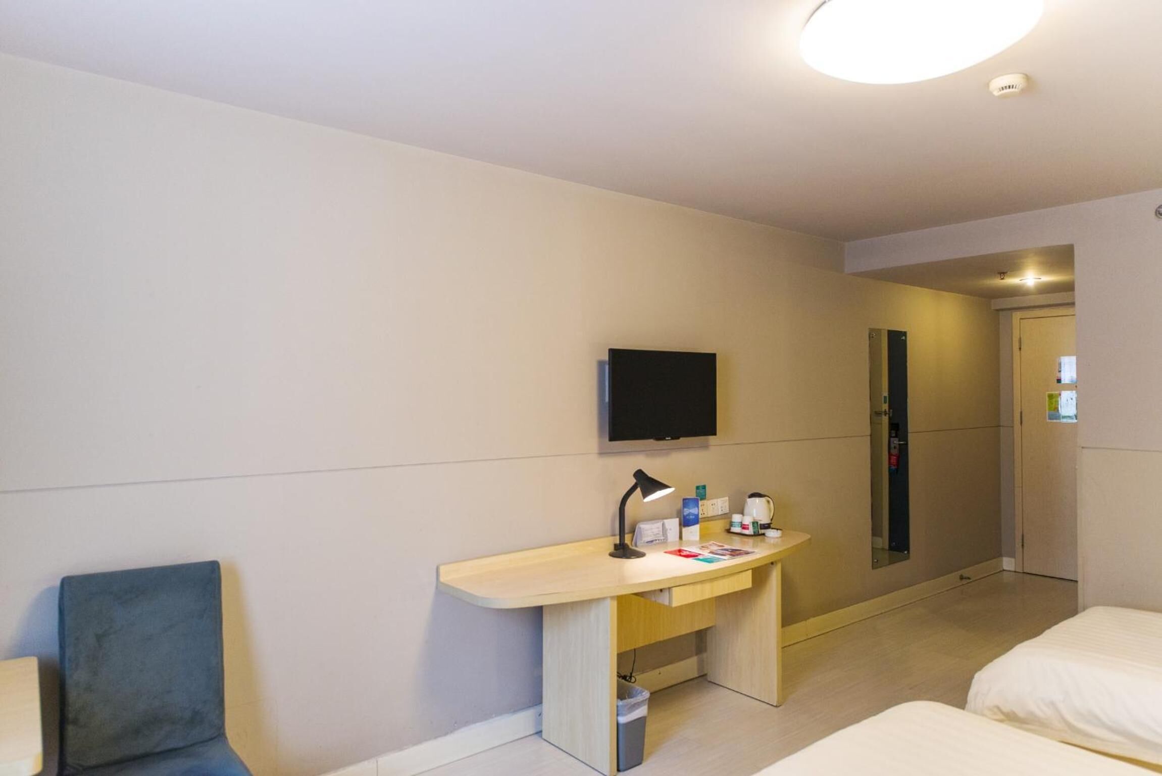 Une chambre d’hôtel avec un lit, un bureau et une chaise, une télévision et une porte.