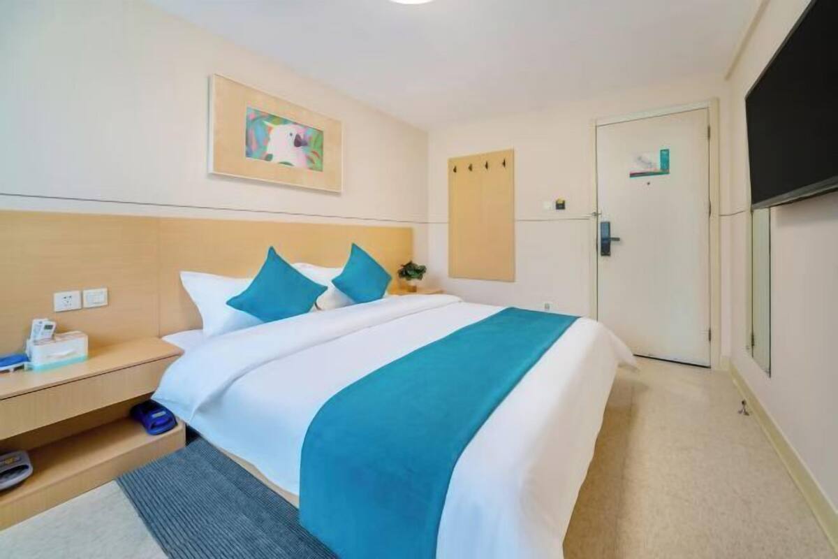Cozy retreat with a neatly made bed, nightstand, and framed picture, perfect for a relaxing stay.