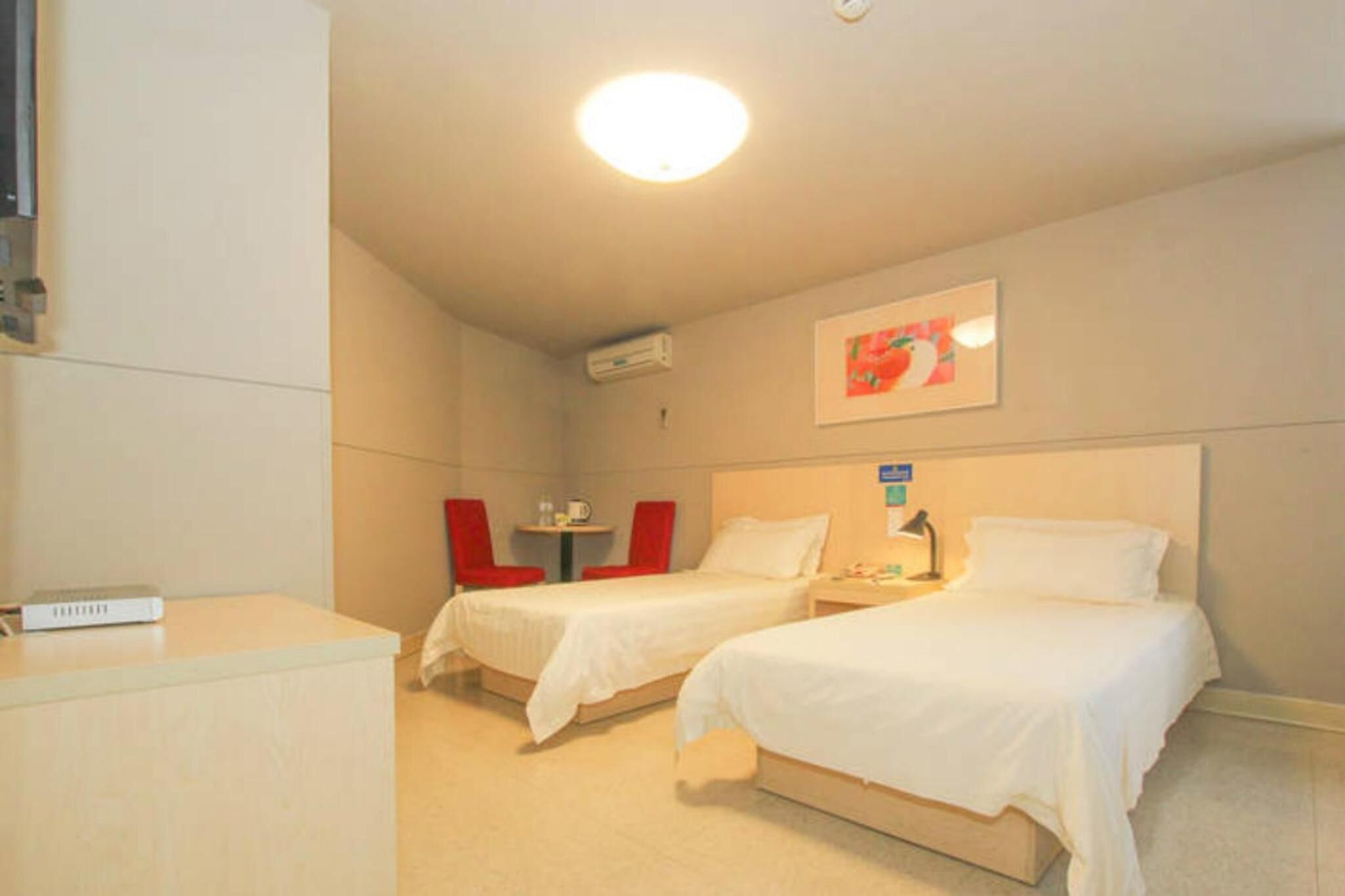 A hotel room with two beds, a desk, a chair, and a small table.