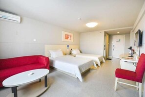 Une chambre d’hôtel avec un lit, un canapé rouge, une petite table et un téléviseur.