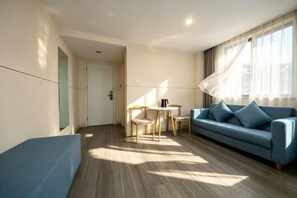 Un salon moderne avec un canapé bleu, une petite table et une porte donnant sur une autre pièce.