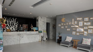 Um saguão moderno de hotel com uma recepção de mármore, obras de arte emolduradas nas paredes e áreas de estar confortáveis.