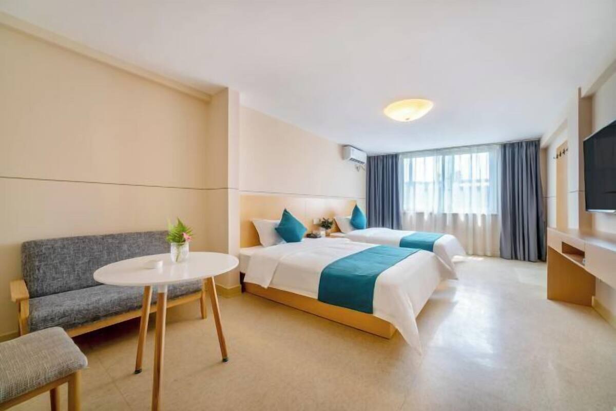 Two single beds, a sofa, and a flat-screen TV are featured in this stylish room.