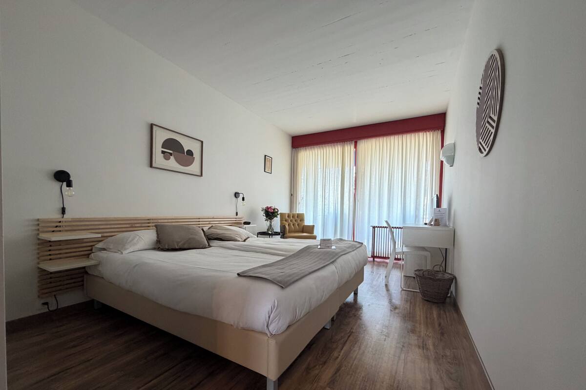 Een moderne hotelkamer met een groot bed, nachtkastjes, een bureau en een stoel.