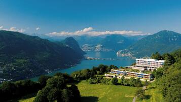Un hotel su più piani, immerso nel verde e circondato da montagne.