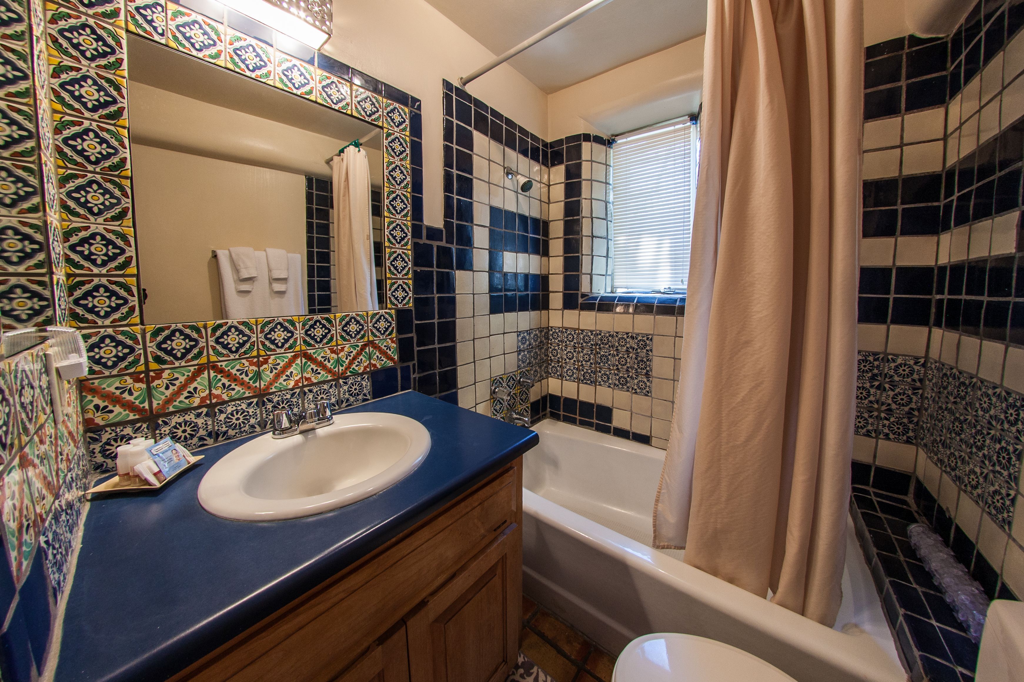 A bathroom with a sink, mirror, and bathtub.