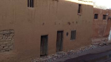 A traditional adobe building with multiple small windows and a stone foundation.