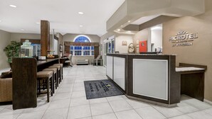 A reception area with a counter, seating, and a large window. - Microtel Inn & Suites by Wyndham Williston (Williston)