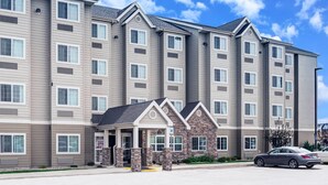 A multi-story hotel with a stone facade entrance, large windows, and a parking lot. - Microtel Inn & Suites by Wyndham Williston (Williston)