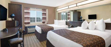 A hotel room with two beds, a desk, a chair, a TV, and a large window with curtains.