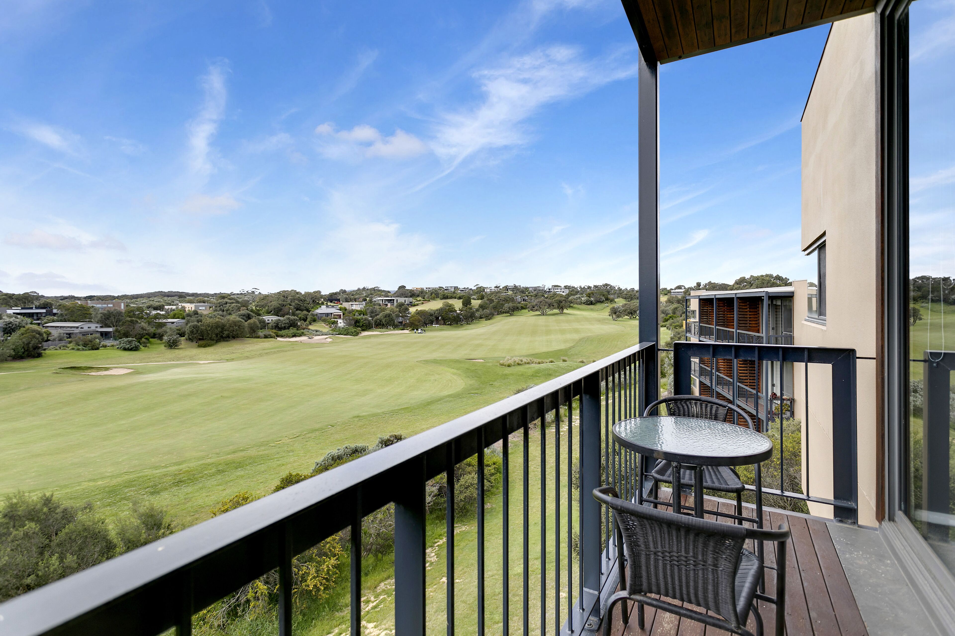 Un balcon donnant sur un terrain de golf, une table à manger et des chaises.